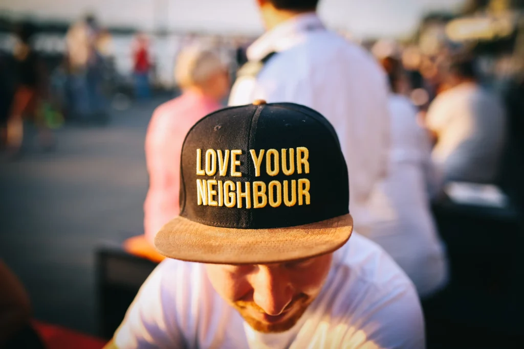 Person med svart keps med texten "Love your neighbour"